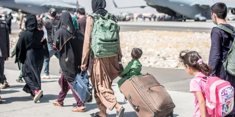 A woman pulls a suitcase with a child sitting on top during an evacuation at Hamid Karzai International Airport, Kabul, Afghanistan, August 24, 2021.  Sgt. Samuel Ruiz/U.S. Marine Corps/Handout via REUTERS THIS IMAGE HAS BEEN SUPPLIED BY A THIRD PARTY.