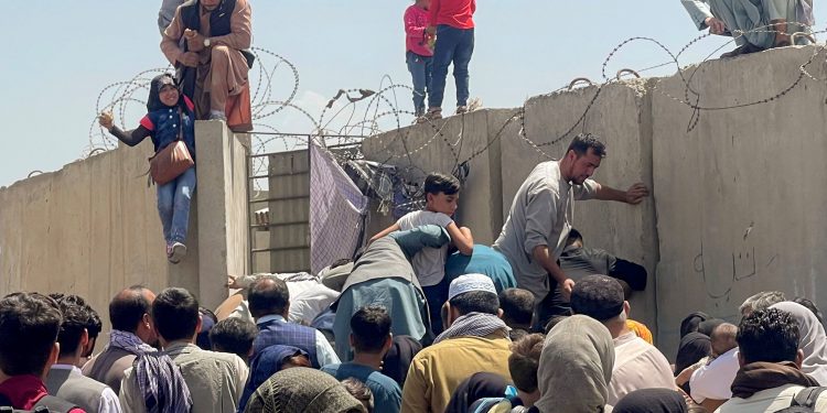 A man pulls a girl to get inside Hamid Karzai International Airport in Kabul, Afghanistan August 16, 2021. REUTERS/Stringer