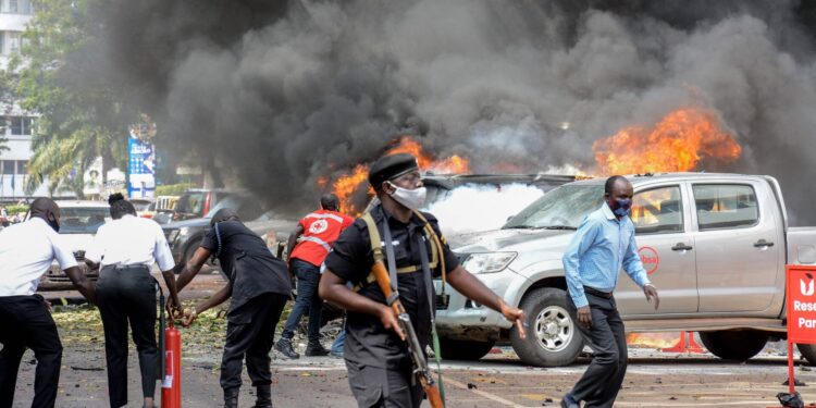 First responders battle to extinguish car fires caused by a suicide bombing near the entrance to Parliament building in Kampala, Uganda, on November 16. Image: AFP.