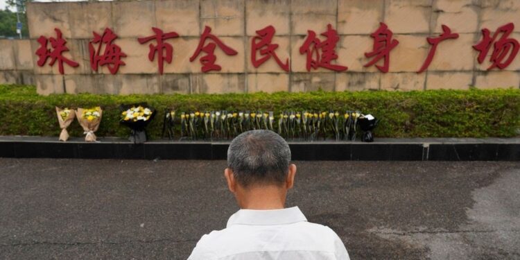 A man stands near flowers laid outside the sports centre where Fan Weiqiu rammed his car into crowds in Zhuhai, China on November 13, 2024.